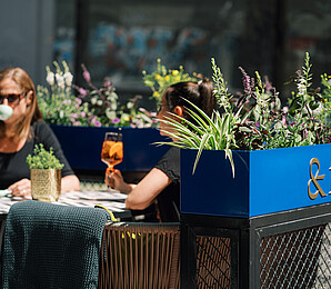 Zwei Personen sitzen im Gastgarten mit Getränk