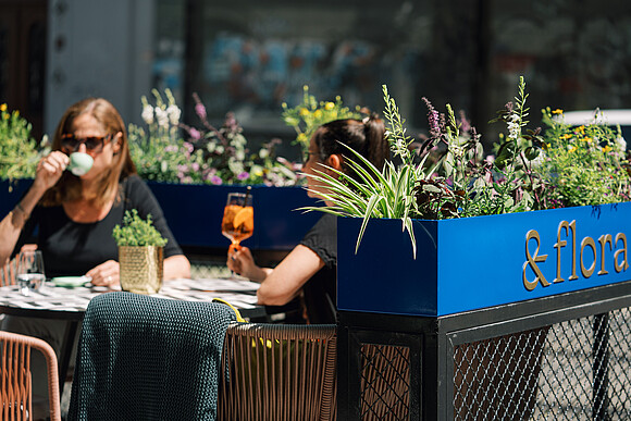 Zwei Personen sitzen im Gastgarten mit Getränk