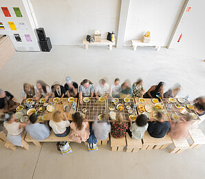 Viele Personen sitzen bei Tisch und essen