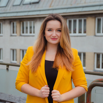 Frau im gelben Blazer lächelt in die Kamera