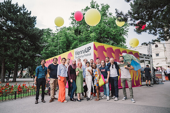 Menschenmenge vor einem Container mit dem Logo der ViennaUP und Ballons auf dem Karlsplatz in Wien.