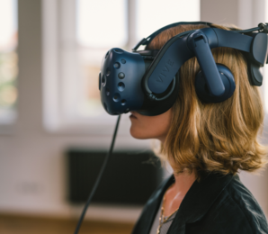 Frau mit rot-blonden Haaren mit und VR Brille im Profil.png