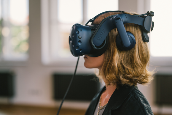 Frau mit rot-blonden Haaren mit und VR Brille im Profil.png