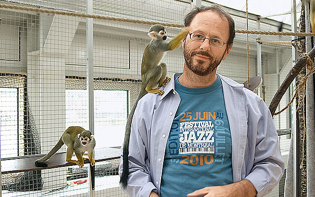 EIn Mann im weißen Kittel kümmert sich liebevoll um zwei Äffchen
