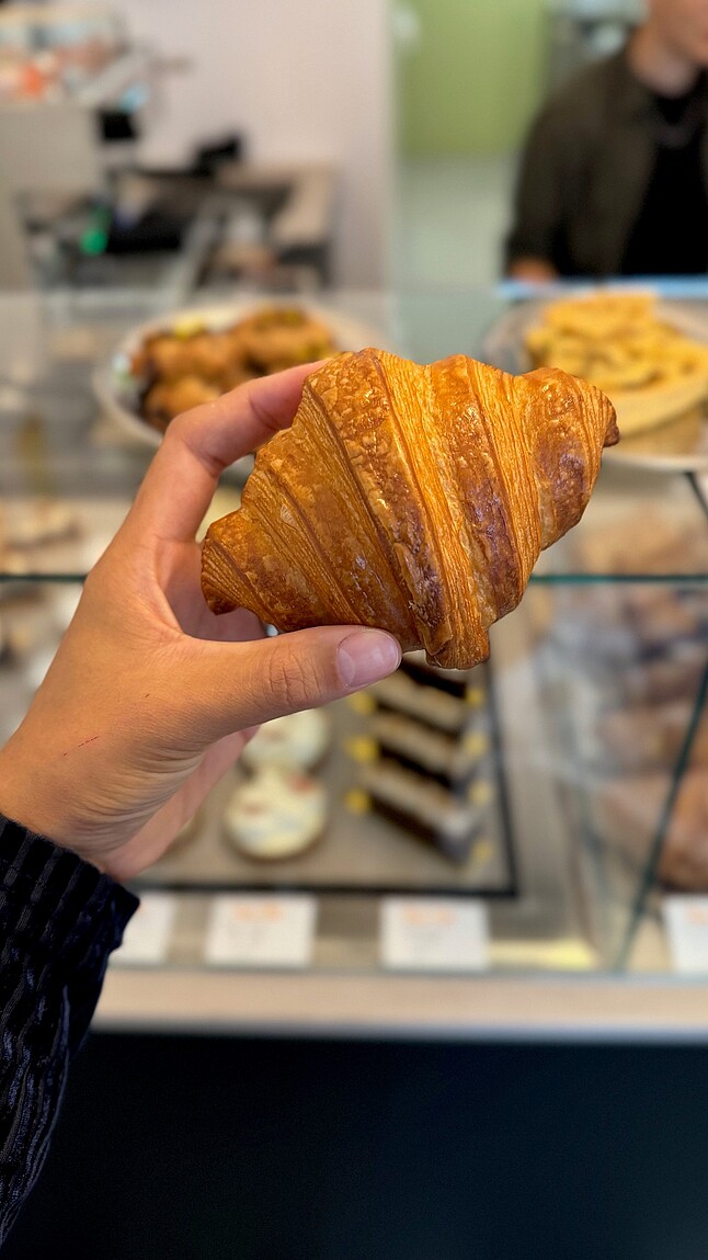 Eine Hand hält ein Croissant. 