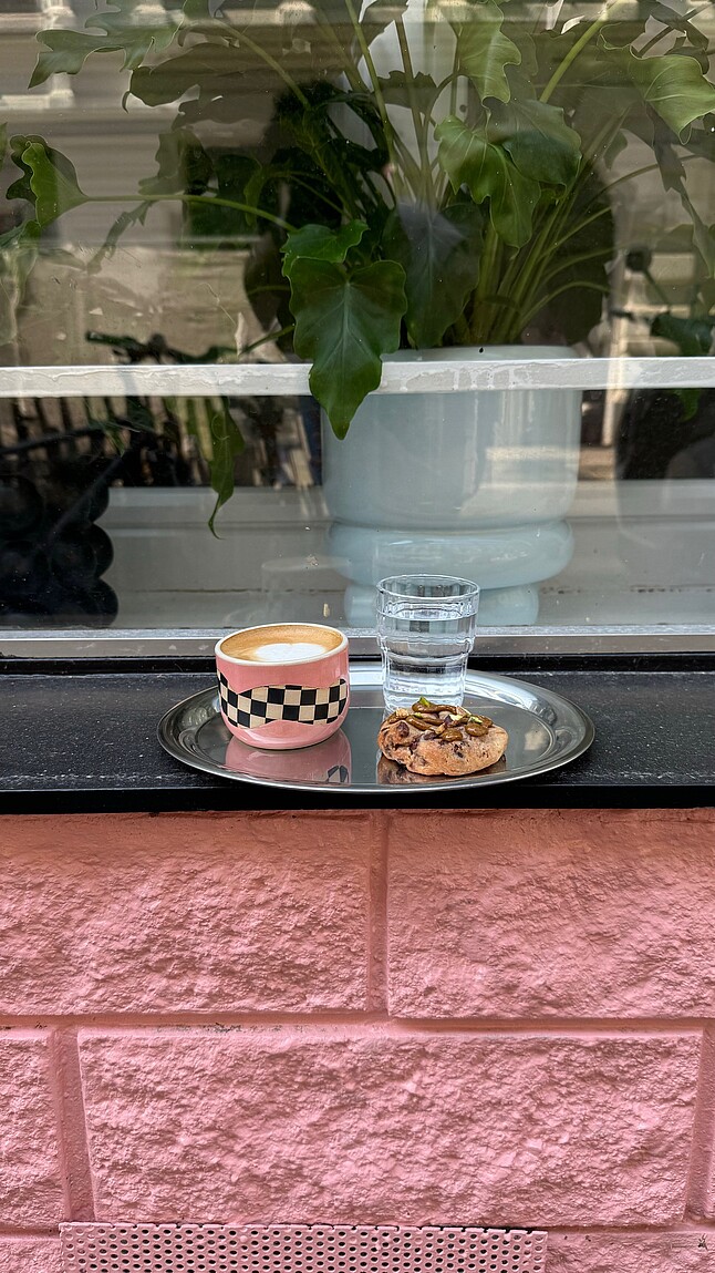 Kaffee und Kuchen auf einem Tablett vor dem Geschäft.